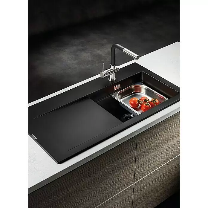 Pyramis Einbauspüle Tekton - 100 x 51 cm, Grau, Linksseitiges Becken - Ein modernes schwarzes Spülbecken mit ausziehbarem Wasserhahn, integrierter Abtropffläche und Edelstahlsieb mit frischen Tomaten in einer hellen Arbeitsplatte.