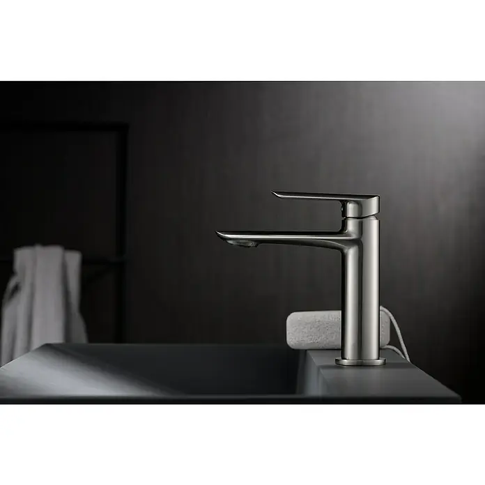 Imex Ural Grifo de lavabo - Níquel - Primer plano de un moderno grifo de baño de níquel cepillado con un elegante caño y palanca sobre un fondo oscuro.