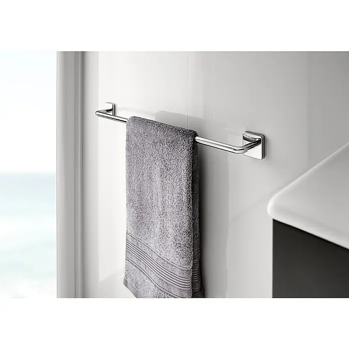 Roca Victoria Toallero - Ancho: 60 cm, Pegado, Resplandeciente - Un toallero cromado con una toalla gris colgada en una pared blanca del baño. Accesorios de baño prácticos para tu hogar.