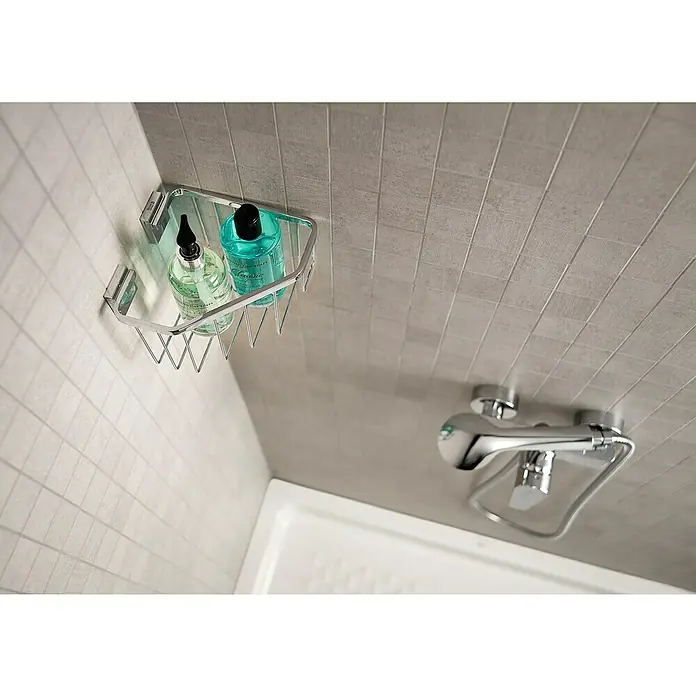 Roca Cesta de baño angular Rubik - 18,7 x 17,5 x 11,4 cm, Cromo - Un estante de baño cromado con dos frascos de productos de cuidado personal está montado en una pared de azulejos. Un grifo cromado también es visible.