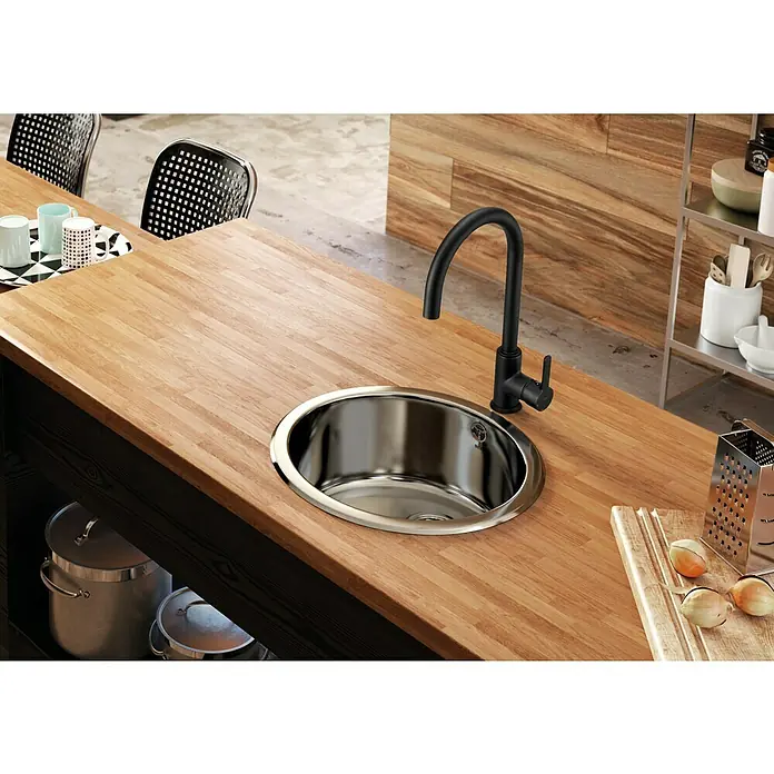 Roca Grifo de cocina Etna Cold Start - Negro - Primer plano de un fregadero de cocina de acero inoxidable con un elegante grifo negro sobre una encimera de madera.