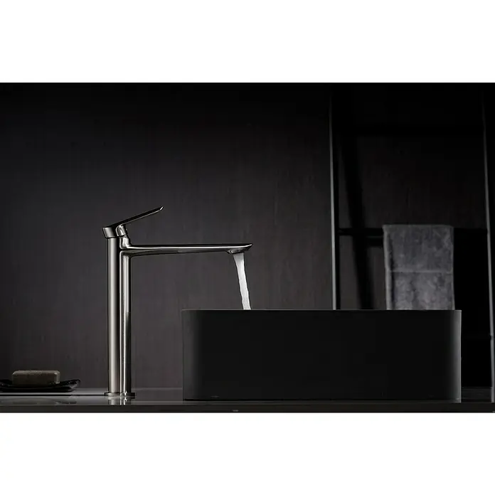 Imex Ural Grifo de lavabo alto - Níquel - Moderno grifo de acero inoxidable vertiendo agua en un lavabo negro con una pastilla de jabón en la encimera.