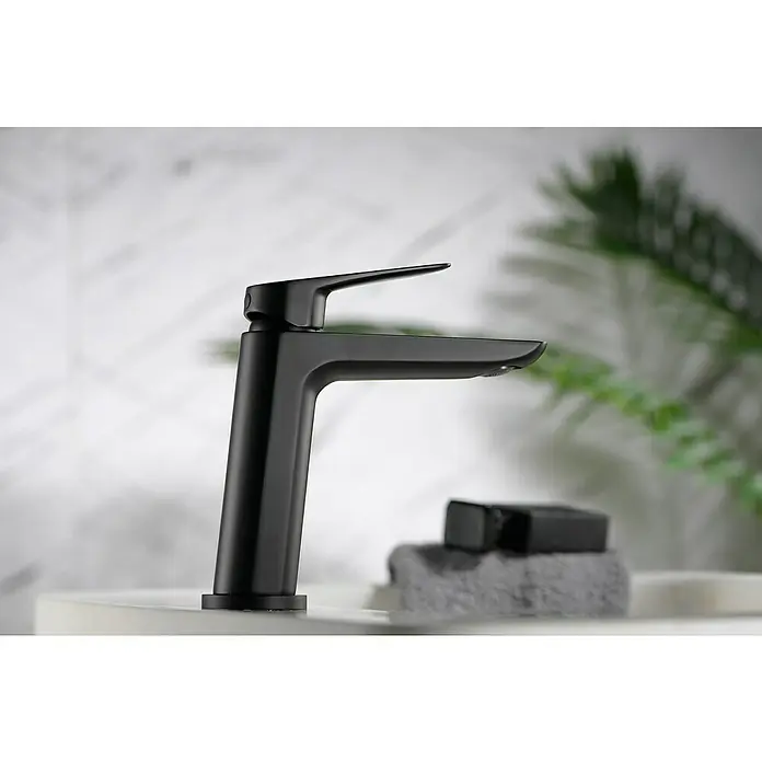 Imex Bélgica Grifo de lavabo - Negro, Mate - Un elegante grifo negro mate descansa sobre una encimera, personificando el diseño moderno de baño. Su forma elegante complementa cualquier baño contemporáneo.