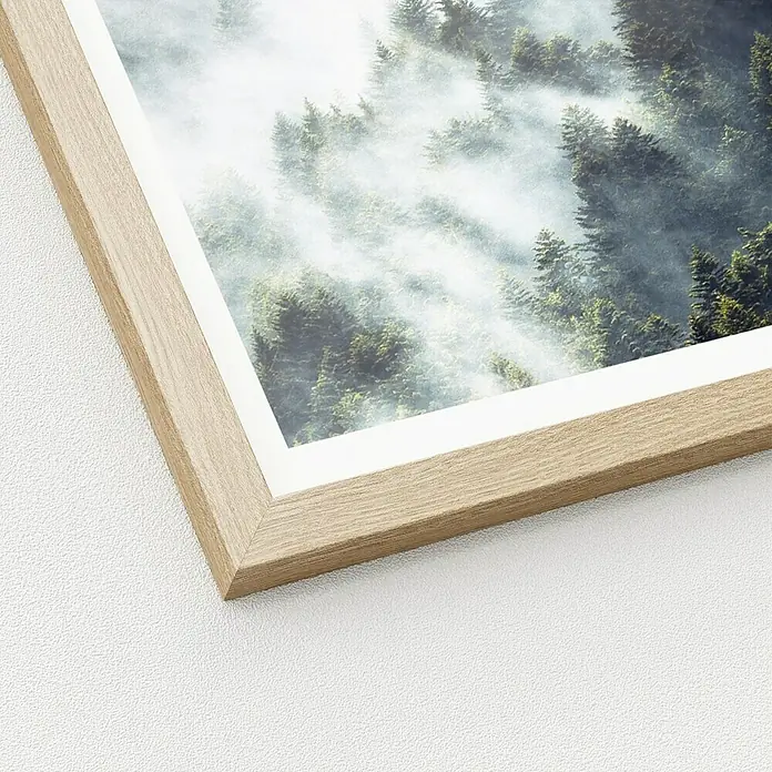 ProArt Bild Slim Scandic - Foggy Trees, B x H: 33 x 33 cm - Nahaufnahme eines gerahmten Kunstdrucks mit einem Waldmotiv im Nebel, der an einer weißen Wand hängt. Der Holzrahmen verleiht dem Bild Wärme.