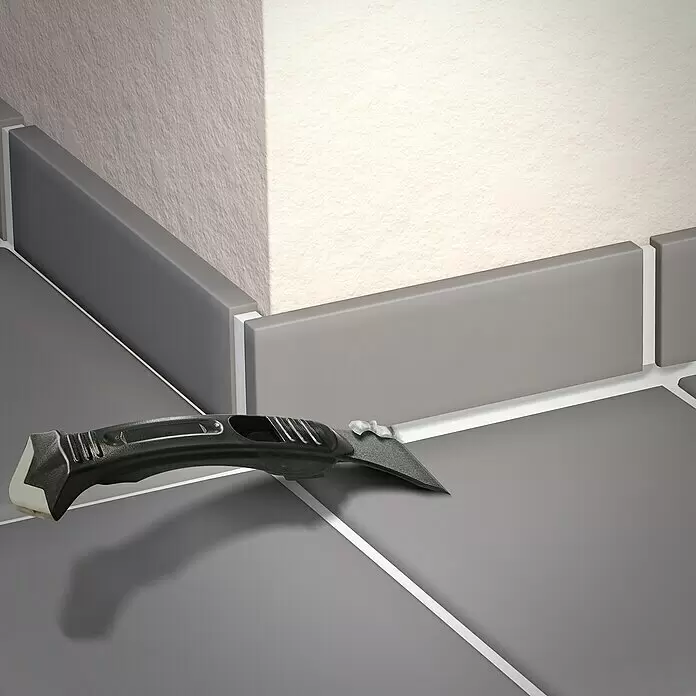 MEM Fugenglätter-Set 3in1 - 3 -tlg. - Schwarzes Fugenwerkzeug zum Entfernen und Verstreichen von Dichtmasse, platziert an einer gefliesten Wand- und Bodenecke.