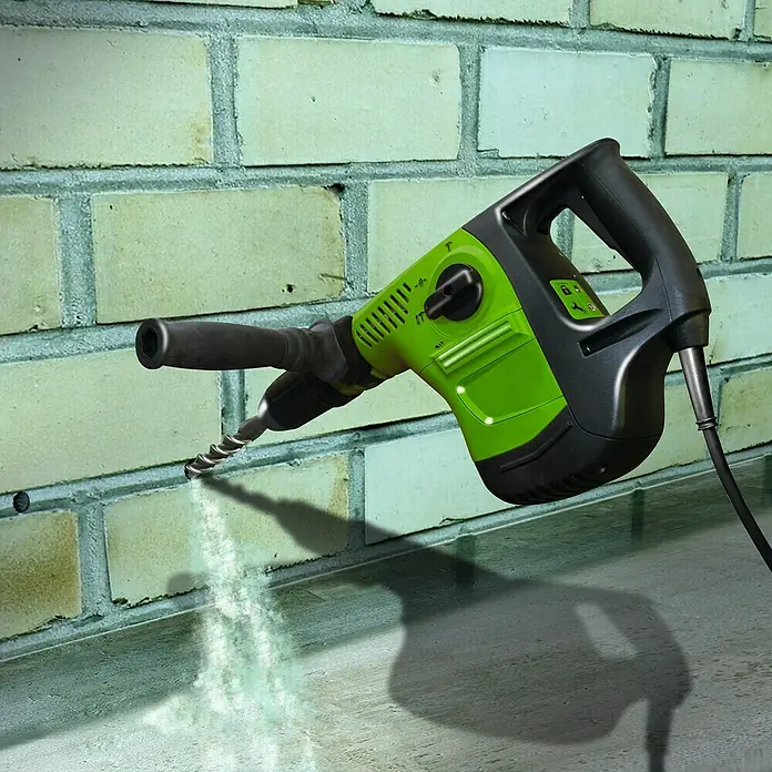MEM Trockene Wand Fix & Fertig - 290 ml - Ein grüner Bohrhammer bohrt ein Loch in eine Ziegelwand. Staub wirbelt dabei auf. Das Gerät ist schwarz abgesetzt und hat ein Kabel.