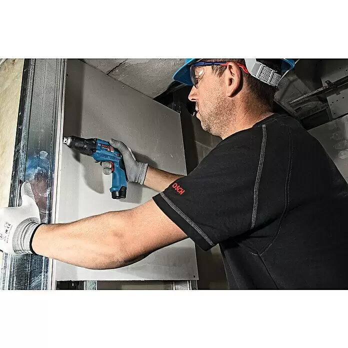 Bosch Professional Akku-Trockenbauschrauber GTB 12V-11 - 12 V, Ohne Akku, Inkl. Koffer - Ein Arbeiter verwendet einen blau-schwarzen Bosch Profi-Bohrschrauber zur Montage einer Trockenbauplatte an einem Metallrahmen.