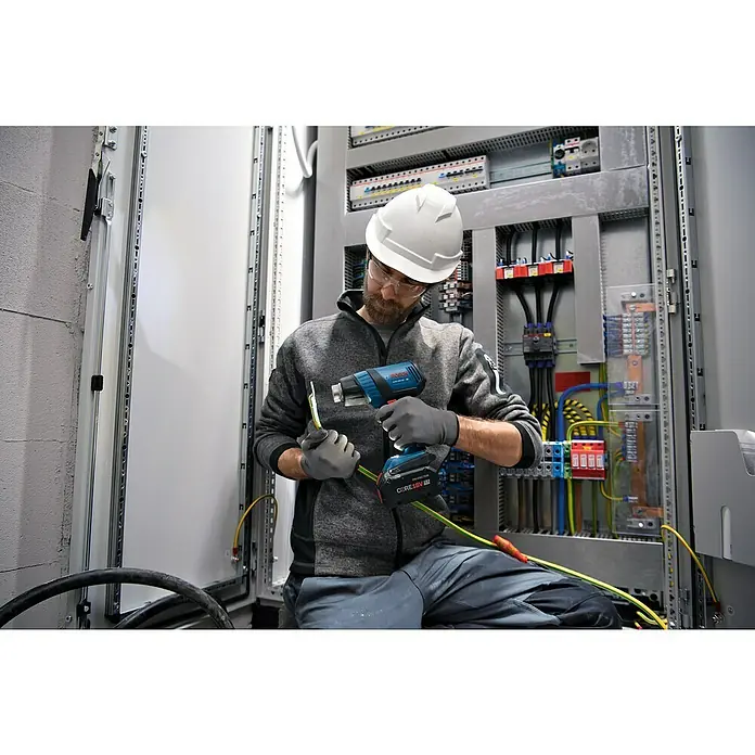 Bosch Professional AMPShare 18V Akku-Heißluftgebläse GHG18V-50 - 18 V, Ohne Akku, Temperaturbereich: 300 °C - 500 °C, Kunststoffkoffer - Ein Elektriker arbeitet mit einem Bosch Heißluftgebläse GHE 18V-50 auf einer Baustelle, um Kabel zu bearbeiten.
