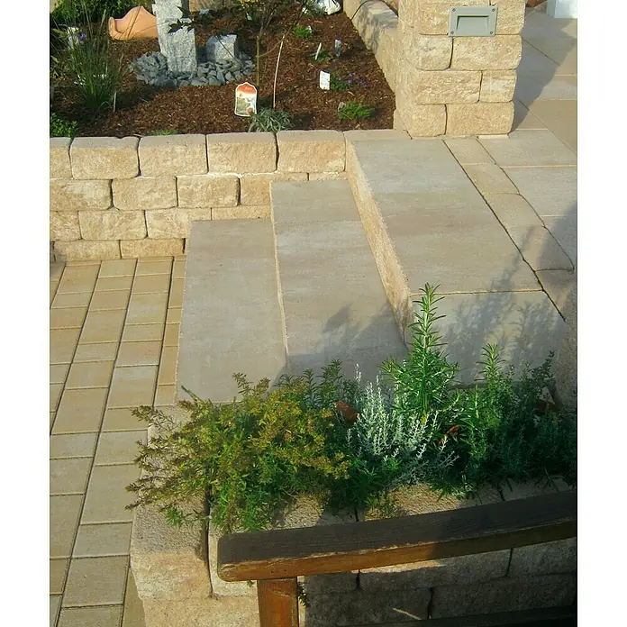 Diephaus Stamford Blockstufe - Sandstein, 100 x 34,5 x 15 cm, Beton - Das Foto zeigt einen angelegten Gartenbereich mit Steinmauern, Stufen und Bepflanzung. Verschiedene Pflanzen und Steine sind dekorativ angeordnet.