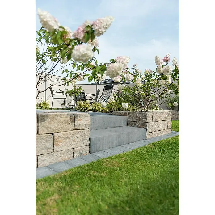 Diephaus Blockstufe Visalia - Quarzit, 100 x 35 x 15 cm, Beton - Aufnahme von stilvollen Steinstufen, die zu einem Gartenbereich mit blühenden Hortensien und Outdoor-Möbeln führen.