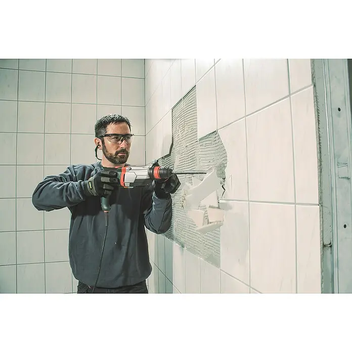 Metabo Holzbohrer - Durchmesser Bohrer: 3 mm - Ein Mann demontiert Fliesen mit einem Bohrhammer, Schutzbrille und Handschuhen. Der Abbruchhammer wird benutzt um Wandfliesen zu entfernen.