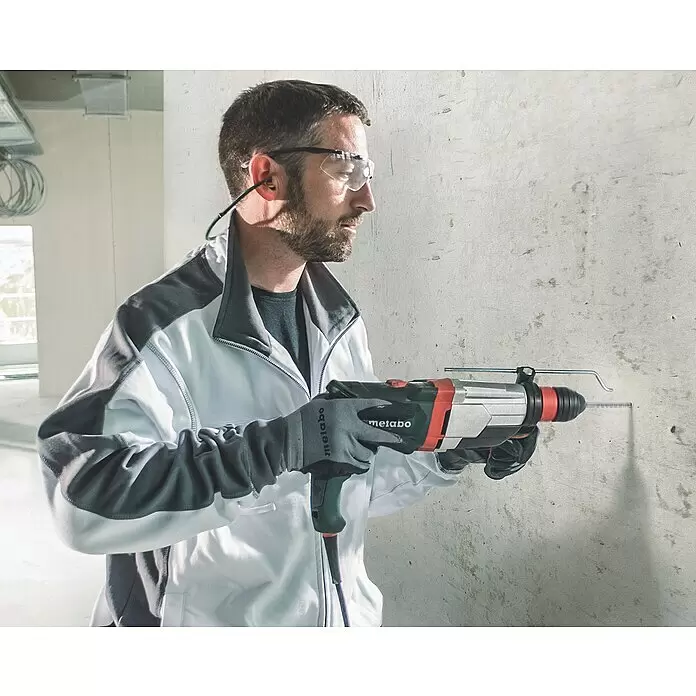 Metabo Holzbohrer - Durchmesser Bohrer: 3 mm - Ein Mann in Schutzkleidung bohrt mit einem rot-silbernen Metabo Bohrhammer in eine Betonwand.
