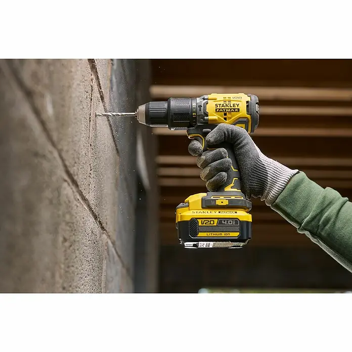 Stanley FatMax Akku SFMCB204-XJ - 18 V, 4 Ah - Aufnahme einer Stanley Fatmax Bohrmaschine in Aktion, die ein Loch in eine Wand bohrt. Das Gerät ist gelb/schwarz und wird mit Akku betrieben.