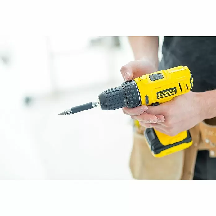 Stanley FatMax Akku-Bohrschrauber FMC011S2-QW - 10,8 V, 2 Akkus, 1,5 Ah, 26 Nm - Person hält einen gelb-schwarzen Stanley FatMax Akkubohrschrauber mit Schrauberbit und Verlängerung, einsatzbereit.