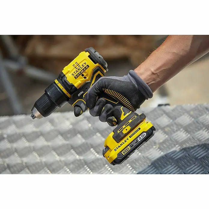 Stanley FatMax Akku-Bohrschrauber SFMCD710D2K-QW - 18 V, 2 Akkus, 2 Ah, 60 Nm - Nahaufnahme eines gelben Stanley Fatmax Akku-Bohrschraubers, der von einer Person mit Handschuhen gehalten wird.
