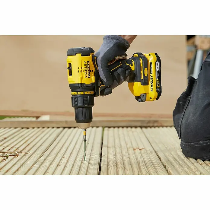Stanley FatMax Akku-Bohrschrauber SFMCD710D2K-QW - 18 V, 2 Akkus, 2 Ah, 60 Nm - Nahaufnahme eines gelben Stanley FATMAX Akku-Bohrschraubers beim Eindrehen einer Schraube in ein Holzdeck.