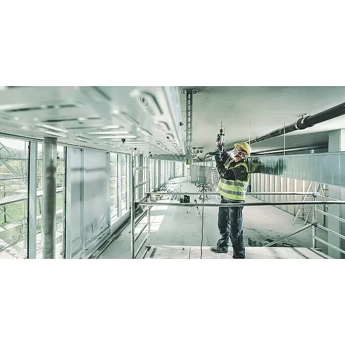 Metabo Martillo combinado 2860 Quick Set - 880 W, 3,2 J, Alojamiento SDS-Plus - Obrero instala un sistema de bandeja de cables metálico con taladro en un techo de obra.