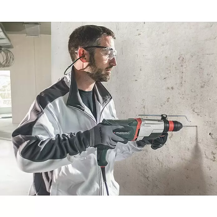 Metabo Martillo combinado 2860 Quick Set - 880 W, 3,2 J, Alojamiento SDS-Plus - Hombre con equipo de seguridad usando un taladro percutor Metabo para perforar una pared de hormigón.