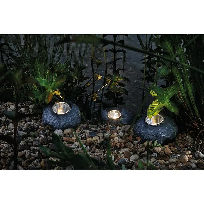 Pontec Teichbeleuchtung LED Set Rocklight 3er Pondostar - 230 V, Warmweiß - Drei graue Gartenleuchten in Steinoptik sind zwischen Pflanzen und Steinen platziert und beleuchten den Bereich stimmungsvoll.