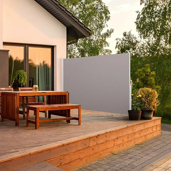 SmartSun Toldo lateral móvil Elegance - Gris piedra, L x Al: 3 x 1,8 m - Imagen de un toldo lateral retráctil en un patio junto a una mesa de comedor. El toldo ofrece privacidad y protección contra el viento.