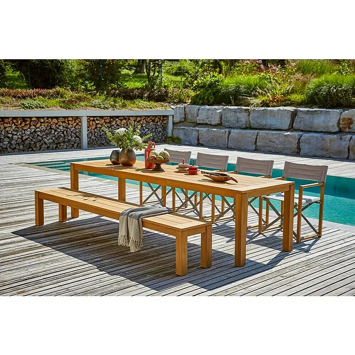 Sunfun Gartenmöbel-Set Laura/Kathrin - 6 -tlg., Akazie/Polyesterfaser/Aluminium, Naturbraun/Hellgrau, Gartenstuhl klappbar - Ein stilvolles Holz-Gartenmöbelset mit einem langen Tisch, einer Bank und Stühlen neben einem Pool, ideal für Mahlzeiten im Freien.