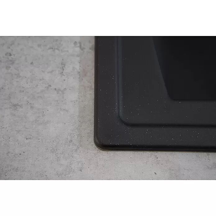 Respekta Einbauspüle Boston - 100 x 50 cm, Schwarz - Nahaufnahme der strukturierten, dunkelgrauen Ecke einer Küchenspüle mit gesprenkelter Oberfläche und abgerundetem Rand.