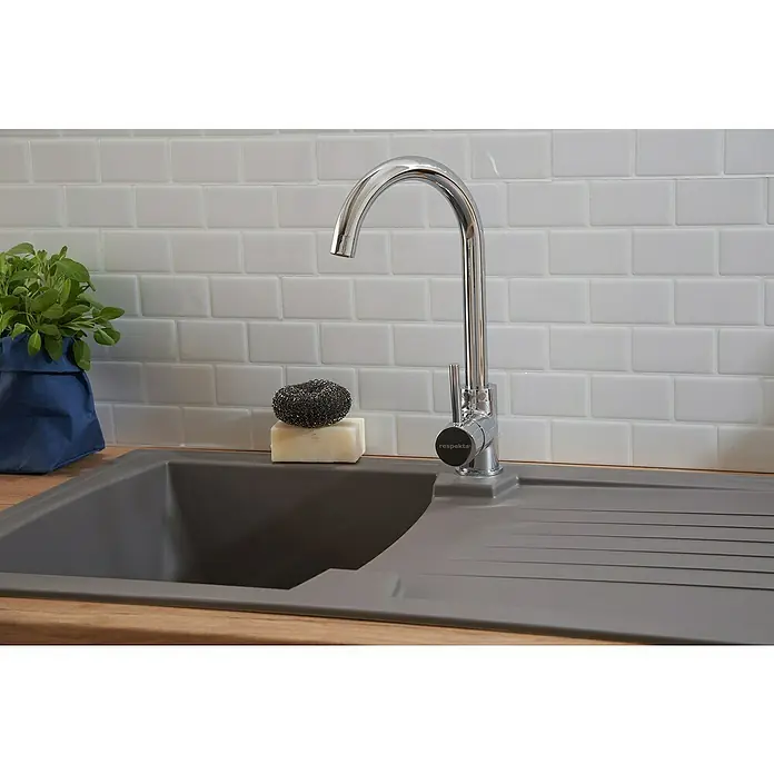 Respekta Einbauspüle Boston - 86 x 50 cm, Betongrau - Ansicht einer Spüle mit Wasserhahn, Seife und einem Topf Kräuter auf einem Holztisch vor weißen Metrofliesen.