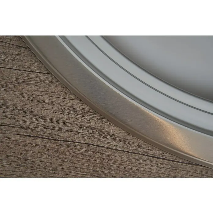 Respekta Einbauspüle Cansas - 77 x 48 cm, Edelstahl - Nahaufnahme eines runden silbernen Tisches mit glatter Oberfläche und Holzmaserung im Hintergrund, die die elegante Gestaltung und Textur des Tisches hervorhebt.