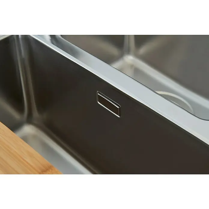 Respekta Fregadero encastrable Chicago - 100 x 50 cm, Acero inoxidable - Primer plano de un fregadero moderno de acero inoxidable con desagüe integrado y una tabla de cortar de madera en primer plano.