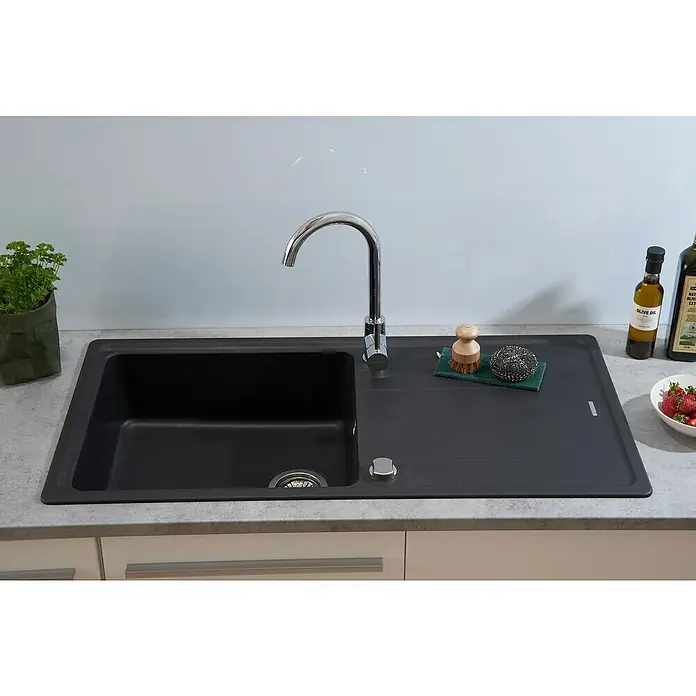 Respekta Einbauspüle Columbia - 100 x 50 cm, Schwarz - Eine moderne, schwarze Küchenspüle mit Abtropffläche, Armatur und einigen Küchenutensilien wie Bürste, Schwamm, Ölflaschen und Erdbeeren.
