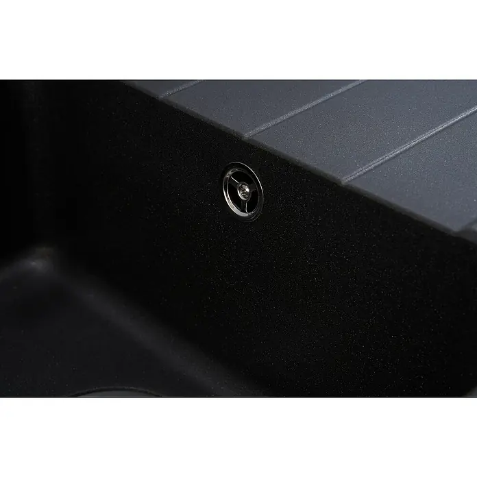 Respekta Einbauspüle Columbia - 100 x 50 cm, Schwarz - Nahaufnahme eines schwarzen Spülbeckens aus Granit mit einem glänzenden, runden Abfluss. Die Oberfläche des Spülbeckens ist leicht strukturiert.