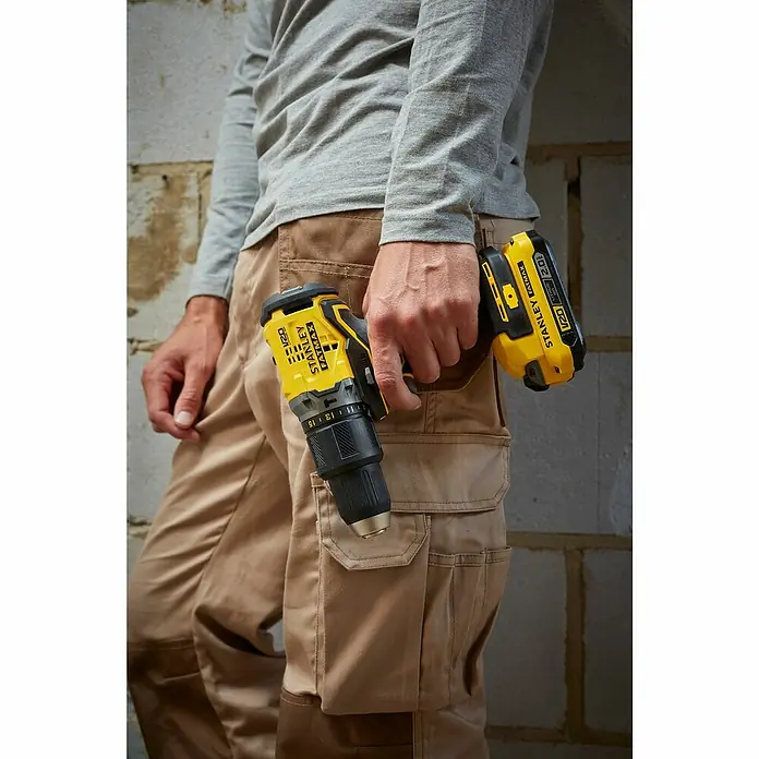 Stanley FatMax Akku-Schlagbohrschrauber SFMCD715D2K-QW - 18 V, 2 Akkus, 60 Nm - Nahaufnahme eines Mannes mit einer gelben Stanley Fatmax Bohrmaschine, die die robuste und zuverlässige Bauweise des Werkzeugs hervorhebt.