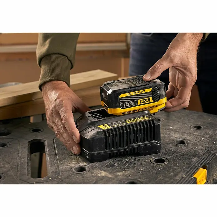 Stanley FatMax Akku SFMCB206-XJ - 18 V, 6 Ah - Das Bild zeigt zwei STANLEY FATMAX V20 Akkus, wobei eine Person einen der Akkus in eine Ladestation einsetzt.