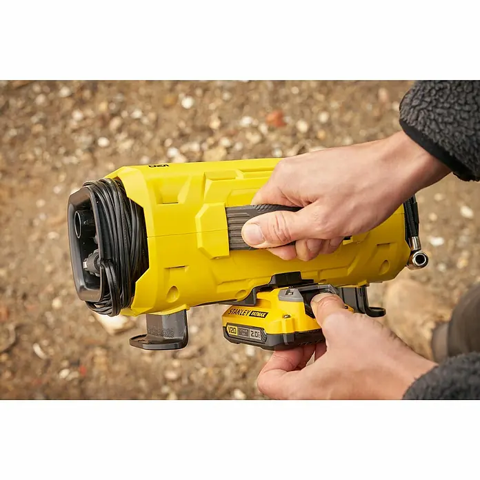 Stanley FatMax Akku-Kompressor SFMCE520B-QW - 18 V, Ohne Akku, 11 bar - Ein gelber Stanley Fatmax Akku-Kompressor wird von zwei Händen gehalten, die den Akku einsetzen.