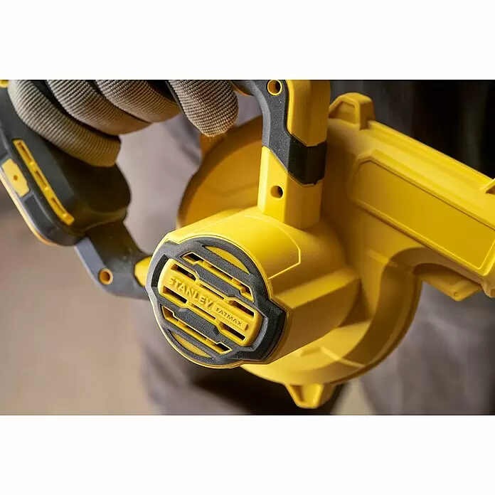 Stanley FatMax Akku-Gebläse SFMCBL01B-XJ - 18 V, Ohne Akku - Eine behandschuhte Hand hält ein gelb-schwarzes Stanley FatMax Gebläse und hebt Griff und Seitenlüfter hervor.