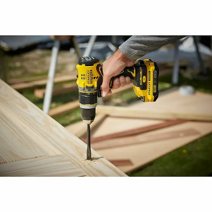 Stanley FatMax Akku-Schlagbohrschrauber SFMCD721B-XJ - 18 V, Ohne Akku, 80 Nm - Nahaufnahme eines gelben Stanley Fatmax Akku-Bohrers beim Bohren in Holz.