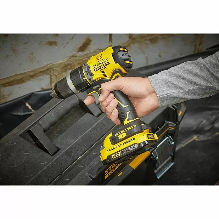 Stanley FatMax Akku-Schlagbohrschrauber SFMCD721D2K-QW - 18 V, 2 Akkus, 2 Ah, 80 Nm - Eine Person hält eine gelb-schwarze Stanley FatMax Akku-Bohrmaschine über einer schwarzen Werkzeugkiste.