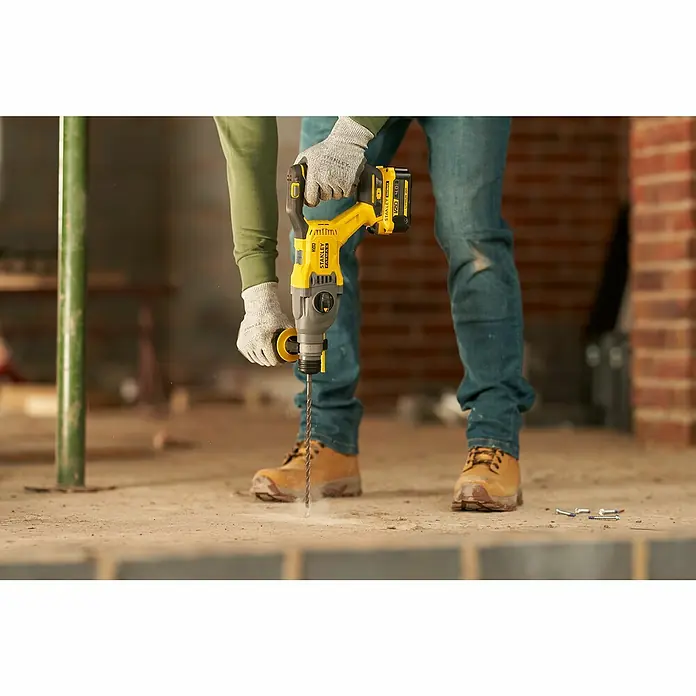 Stanley FatMax Akku-Kombihammer SFMCH900M22-QW - 18 V, 2 Akkus, 4 Ah, 2 J - Nahaufnahme eines Mannes, der mit einer gelben Stanley Fatmax SDS-Hammerbohrmaschine in einen Betonboden bohrt.