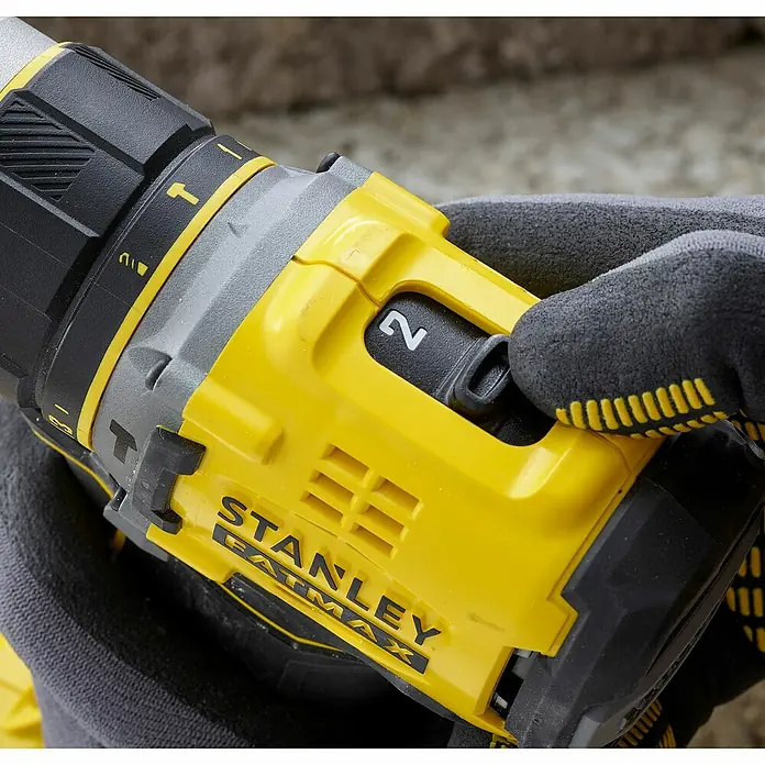 Stanley FatMax Akku-Schlagbohrschrauber SFMCD721D2K-QW - 18 V, 2 Akkus, 2 Ah, 80 Nm - Nahaufnahme eines gelben STANLEY FATMAX Akku-Bohrschraubers in der Hand eines Arbeiters mit Handschuhen.