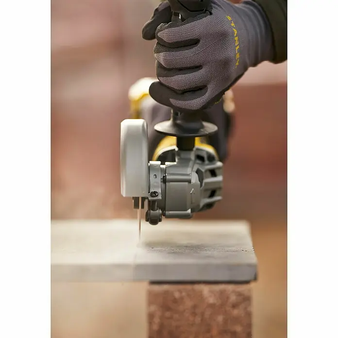 Stanley FatMax Akku-Winkelschleifer SFMCG700M2K-QW - 2 Akkus, 4 Ah, Durchmesser Scheibe: 125 mm - Nahaufnahme einer Hand, die mit einer Stanley-Trennsäge einen Stein schneidet. Staubpartikel sind in der Luft zu sehen.