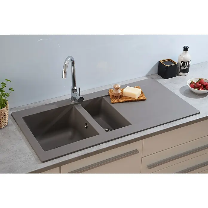 Respekta Einbauspüle Denver - 50 x 100 cm, Anzahl Becken: 1,5 Stk., Betongrau - Nahaufnahme einer modernen, grauen Küchenspüle mit zwei Becken, einem Chromhahn und einigen Küchenutensilien.