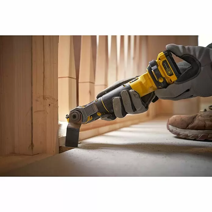 Stanley FatMax Akku-Multifunktionswerkzeug SFMCE500D2K-QW - 18 V, 2 Akkus, 2 Ah - Eine behandschuhte Hand benutzt ein gelb-schwarzes oszillierendes Multitool, um Holzrahmen nahe dem Boden zu schneiden.