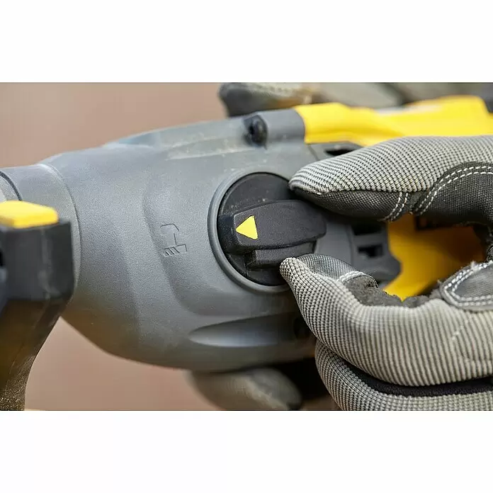 Stanley FatMax Akku-Kombihammer SFMCH900M22-QW - 18 V, 2 Akkus, 4 Ah, 2 J - Hand in grauem Handschuh stellt schwarzen Moduswahlschalter mit gelbem Pfeil an grau-gelbem Elektrowerkzeug ein.