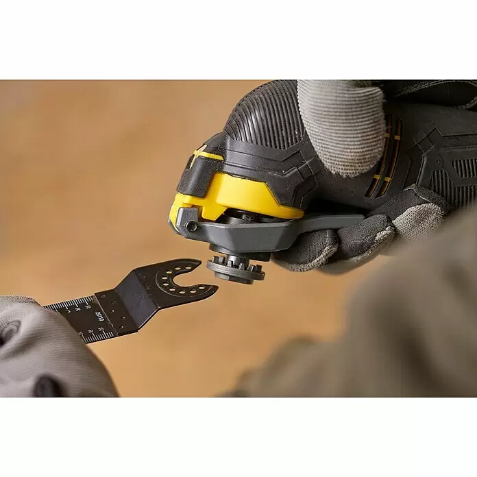 Stanley FatMax Akku-Multifunktionswerkzeug SFMCE500B-XJ - 18 V, Ohne Akku - Behandschuhte Hände befestigen ein schwarzes oszillierendes Sägeblatt mit Messmarken an einem schwarz-gelben Oszillations-Multitool.