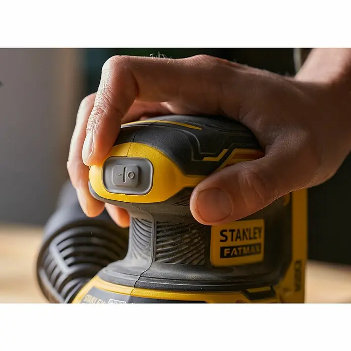 Stanley FatMax Akku-Exzenterschleifer SFMCW220B-XJ - 18 V, Ohne Akku, Durchmesser Schleifteller: 125 mm - Nahaufnahme eines gelb-schwarzen Stanley Fatmax Schleifers, der von einer Hand bedient wird.