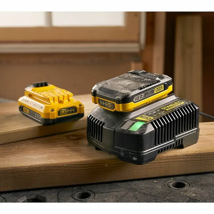 Stanley FatMax Akku SFMCB202-XJ - 18 V, 2 Ah - Ein STANLEY FATMAX V20 2.0Ah Akku lädt auf einem Ladegerät, während ein zweiter Akku daneben liegt.