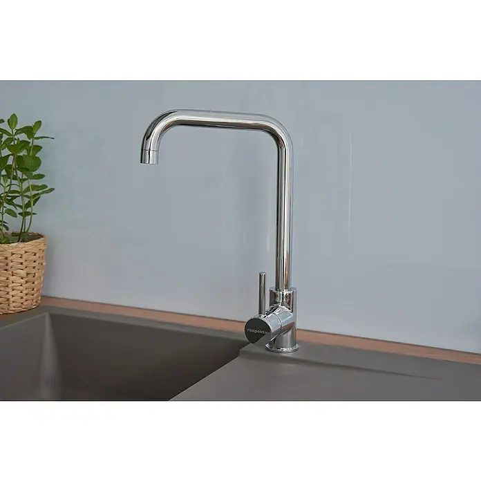 Respekta Einbauspüle Denver - 78 x 43,5 cm, Grau - Nahaufnahme eines modernen, verchromten Respekta Wasserhahns an einer grauen Spüle, ergänzt durch eine grüne Pflanze im Hintergrund.