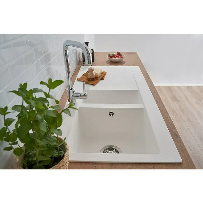 Respekta Einbauspüle Denver - 50 x 100 cm, Anzahl Becken: 1,5 Stk., Weiß - Nahaufnahme einer weißen Doppelspüle mit Abtropffläche und Armatur, neben einer Kräuterpflanze und einem Teller Erdbeeren.