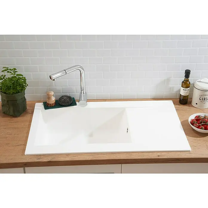 Respekta Einbauspüle Denver - 86 x 50 cm, Weiß, Anzahl Becken: 1 Stk. - Einbauküchenspüle aus weißem Material mit Armatur, Spülbürste, Kräutertopf, Olivenöl, Knoblauchbehälter und Tomaten auf einer hölzernen Arbeitsplatte.