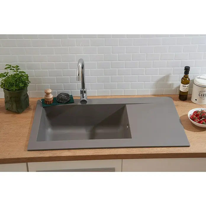 Respekta Einbauspüle Denver - 86 x 50 cm, Betongrau, Anzahl Becken: 1 Stk. - Spültisch in stilvollem Grau mit modernem Wasserhahn, Spülutensilien und frischen Kräutern auf einer hellen Holzoberfläche vor weißen Fliesen.